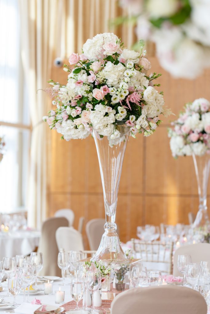 tall table centre in glass vase with mini vases at base .Pink.white