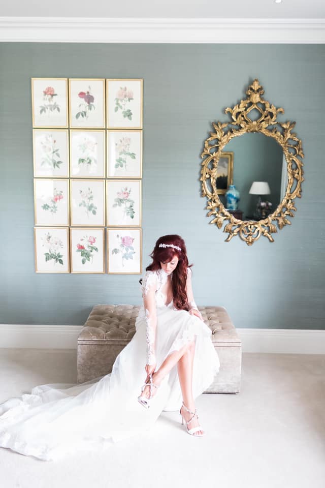 Bride putting her shoes on, sitting in the bridal suite