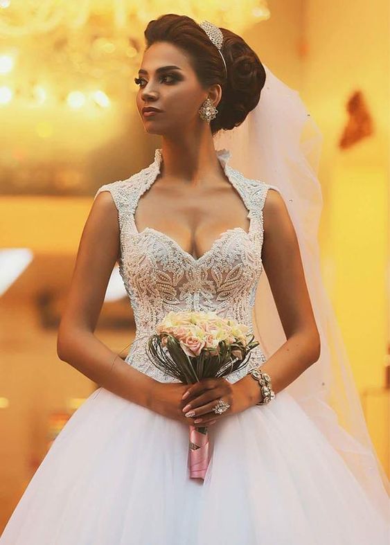 Bride wearing a Queen Anne neckline dress and holding a bouquet